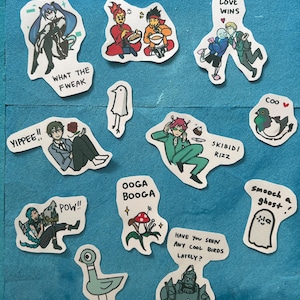 May include: A collection of colorful stickers with various cartoon illustrations and text. The stickers feature characters, phrases like "LOVE WINS", "WHAT THE FWEAK", and "POW!!", and images of birds, ghosts, and other whimsical designs.