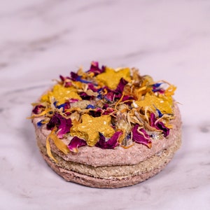 May include: A layered dog treat topped with dried flowers and star-shaped biscuits.