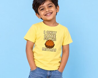 May include: A bright yellow short-sleeved t-shirt featuring a graphic of an orange-colored sweet treat in a brown paper liner, with the text "I ONLY CAME FOR THE MITHAI" printed in dark brown block letters above and below the illustration.