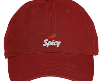 May include: A dark red baseball cap featuring an embroidered design on the front. The design consists of a small red chili pepper icon positioned above the white text that reads Spicy in a casual, rounded script font style.