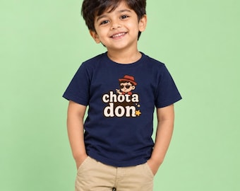 May include: A navy blue short-sleeved t-shirt featuring a graphic print of a cartoon character wearing a red hat and sunglasses, with the text "chota don" in a stylized cream-colored font and a small yellow star icon below the lettering.