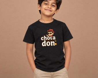 May include: A black short-sleeved t-shirt featuring a graphic of a cartoon character wearing a red hat and sunglasses, with the text "chota don" printed in white letters above a small yellow star icon on the center of the chest.