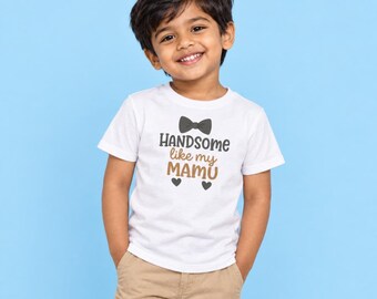 May include: A white short-sleeved t-shirt featuring a black bow tie graphic above the text "HANDSOME like my MAMU" in black and brown lettering, with two small black heart icons positioned below the text on the front of the garment.