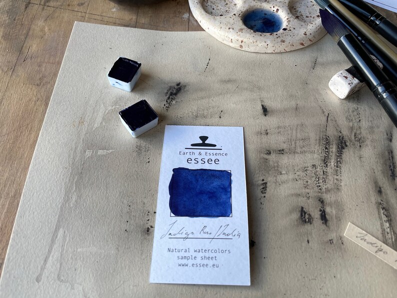Op de afbeelding: Een monstersheet voor Indigo Blue aquarelverf van Earth & Essence essee. Het blad toont een klein vierkantje van de verf en de tekst "Indigo Blue/Indigo" in cursief.
