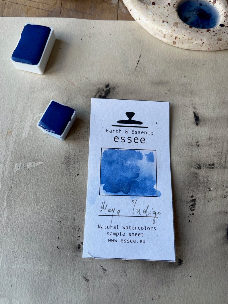 Op de afbeelding: Een monsterblad voor Maya Indigo natuurlijke aquarelverf. Het blad toont een blauwe aquarelwas met de tekst "Maya Indigo" en "Natural watercolors sample sheet www.esseee.eu" eronder.
