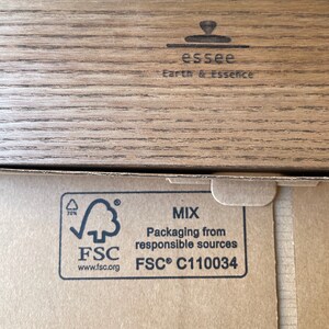 May include: Close-up of a cardboard box with the text "essee Earth & Essence" and the FSC logo. The box has a wood grain pattern on the top and the FSC logo with text indicating packaging from responsible sources.