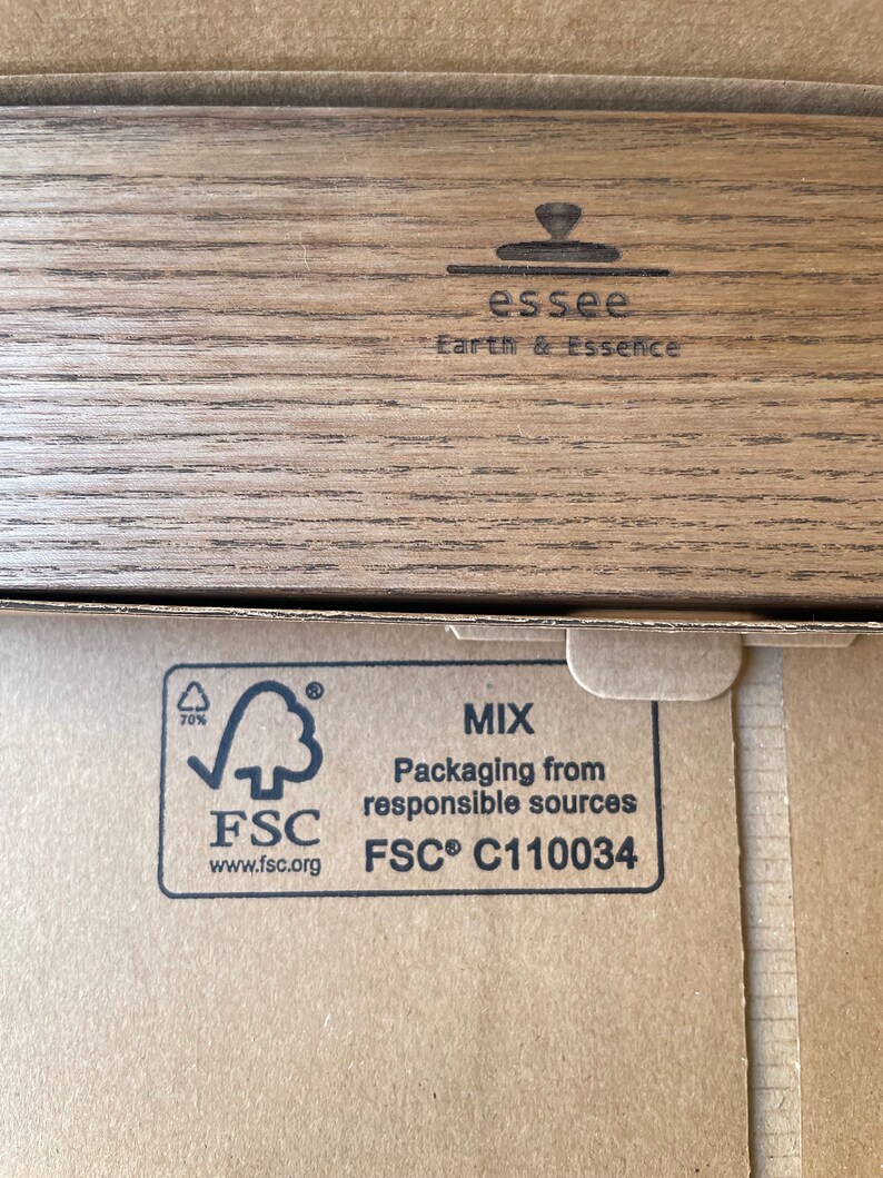 May include: Close-up of a cardboard box with the text "essee Earth & Essence" and the FSC logo. The box has a wood grain pattern on the top and the FSC logo with text indicating packaging from responsible sources.