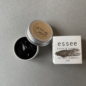 Pu&ograve; includere: Un piccolo contenitore argentato di pigmento nero etichettato "Nero di Roma" dal marchio "essee Earth & Essence". L'etichetta riporta anche "Pigmenti antichi 5ml".