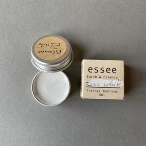 Pu&ograve; includere: Un piccolo contenitore rotondo d'argento con un'etichetta bianca che dice "Blance Zinc" e un'etichetta marrone che dice "essee Earth & Essence Zinc White Tierras Ibericas 5ml".