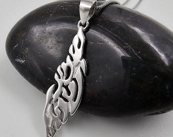 May include: A silver pendant featuring a detailed, abstract design resembling a stylised flame or feather. The pendant is hanging from a silver chain on a black stone.