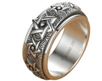 Op de afbeelding: Een zilveren ring met een draaibare band met een gedetailleerd ontwerp van een zespuntige ster. De band is gegraveerd met draaiende patronen en de binnenkant van de ring is gemarkeerd met "S990 20".