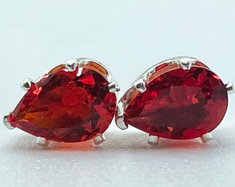 May include: A pair of silver earrings with red pear-shaped gemstones.