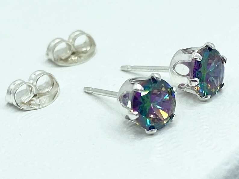 Puede incluir: Un par de pendientes de plata con piedras redondas iridiscentes. Los pendientes tienen un dise&ntilde;o sencillo con un peque&ntilde;o engaste redondo para las piedras.