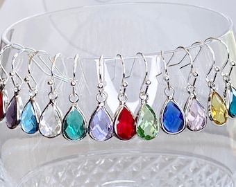 May include: A set of ten teardrop-shaped dangle earrings with silver hooks. The earrings feature faceted gemstones in a variety of colors, including red, blue, green, purple, and clear.