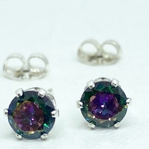 Puede incluir: Un par de pendientes de plata con una piedra preciosa redonda e iridiscente en el centro. La piedra preciosa presenta un arco&iacute;ris de colores, incluyendo morado, verde y azul.