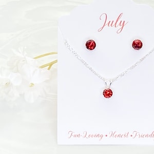 May include: A silver necklace and earrings set with a red gemstone. The card says "July" and "Fun-Loving, Honest, Friendly".