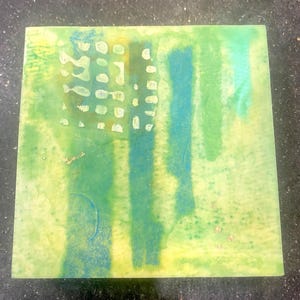 Può includere: Una piastrella quadrata con una miscela di lavaggi in stile acquerello verde lime, giallo e verde acqua. La superficie presenta una griglia di piccoli segni circolari chiari nel quadrante in alto a sinistra, strisce verticali e accenti dorati.