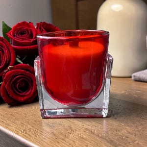 May include: A white ceramic mug with a black handle and the text "But First, Coffee" in a bold, black font. The mug is set against a neutral background, highlighting its simple design.