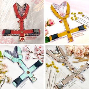May include: Four different dog harnesses with floral patterns. The harnesses are in red, yellow, green, and beige. The harnesses have adjustable straps and a buckle closure. The harnesses are made of fabric and have a metal ring for attaching a leash. The text on the harnesses reads "STOFF: HERBSTBLUMEN GURTBAND: ROSTROT", "STOFF: VIRGIN FLEUR GURTBAND: SENFGELB", "STOFF: KIRSCHBL&Uuml;TEN GRAD SURTBAND: MINT", and "STOFF: VINTAGE DAISIES GURTBAND: SAND".