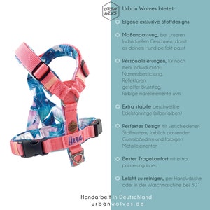 May include: A pink and blue dog harness with a floral pattern. The harness has a name tag that says "Hera". The harness is made with high-quality materials and features a sturdy design. It is adjustable and has a comfortable fit for your dog.