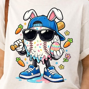 May include: White t-shirt featuring a baseball character with bunny ears, sunglasses, and a baseball bat. The character is holding a decorated Easter egg and is wearing a blue cap and sneakers. Carrots and flowers are also included in the design.
