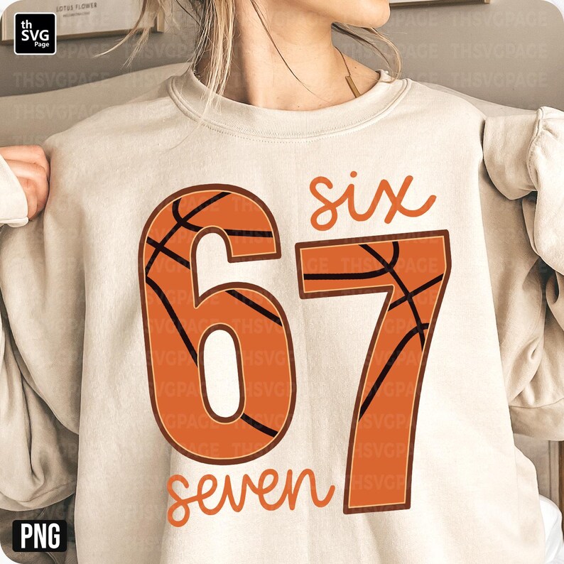 May include: A beige sweatshirt featuring the numbers "67" in a basketball design, with the word "six" above and "seven" below in a handwritten font. The basketball design is orange with black lines. The sweatshirt is a neutral color.