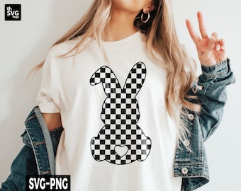 May include: A white t-shirt with a black and white checkered bunny silhouette with a small heart in the center. The bunny is facing the left side of the image. The t-shirt is being worn by a person with long blonde hair.