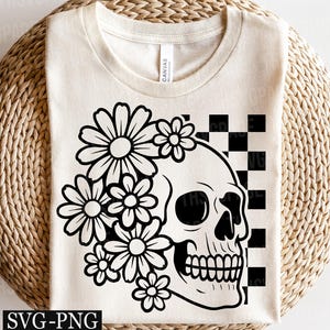May include: Cream-colored t-shirt featuring a black and white graphic of a skull adorned with daisies, set against a checkered background. The design includes the text "SVG-PNG" at the bottom. A casual, floral-themed design.