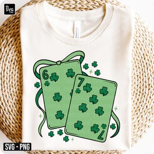 May include: A cream-colored t-shirt featuring a St. Patrick's Day design. The design includes two green playing cards with shamrocks, the numbers 6 and 7, and green ribbons. The text "SVG - PNG" is in the bottom left corner.