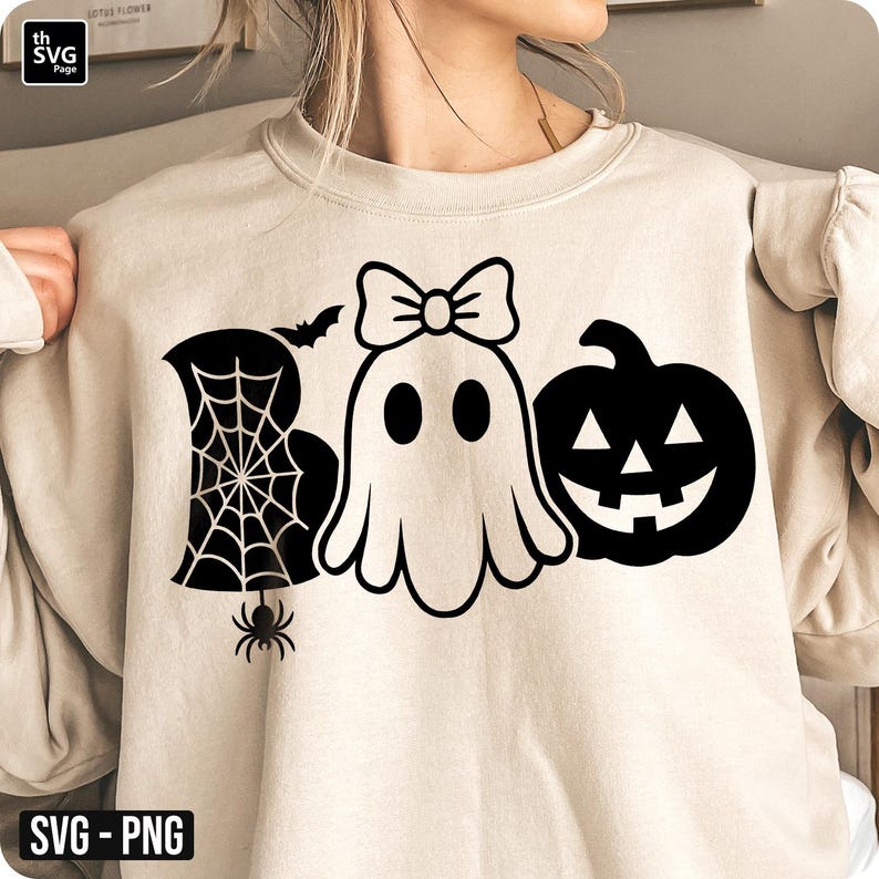May include: Beige sweatshirt with a black Halloween-themed graphic. The graphic includes the word "BOO" with a spider web, a ghost with a bow, a bat, a spider, and a jack-o'-lantern. The design is in a simple, clean style.