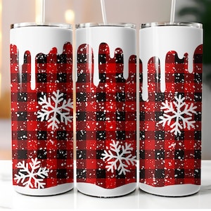 Op de afbeelding: Drie witte roestvrijstalen bekers met een rood-zwart buffalo plaid-patroon en witte sneeuwvlokken. De bekers hebben een wit druppeleffect aan de bovenkant.