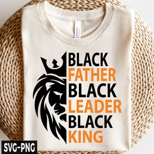 Puede incluir: Una camiseta blanca con un gr&aacute;fico de le&oacute;n negro y el texto "Black Father Black Leader Black King" en naranja y negro.