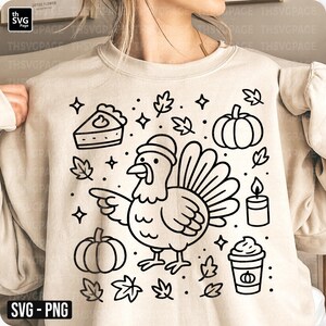 Op de afbeelding: Beige sweatshirt met een zwart-wit Thanksgiving-thema grafiek. Het ontwerp bevat een kalkoen, pompoenen, taart, bladeren, een kaars en een koffiekopje. De tekst "SVG - PNG" staat linksonder.