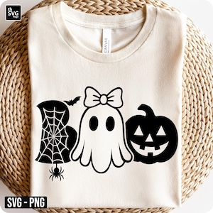 May include: Cream-colored t-shirt with a Halloween-themed graphic. The design features the word "BOO" with a spider web, ghost with a bow, and a jack-o'-lantern. The shirt has a crew neck and short sleeves. The text "SVG - PNG" is in the bottom left corner.