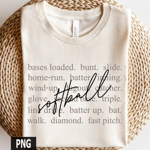 May include: Cream-colored t-shirt with the word "softball" in a cursive font. The shirt features a list of softball terms in a gray font, including "bases loaded," "home-run," and "fast pitch."
