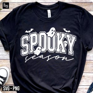 Puede incluir: Camiseta negra con la frase "Spooky Season" en blanco, con gr&aacute;ficos de fantasmas y murci&eacute;lagos. El texto tiene un aspecto desgastado, perfecto para Halloween.