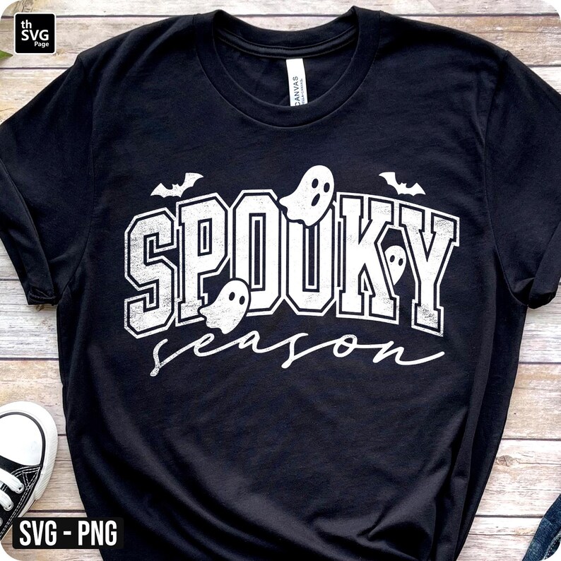 Puede incluir: Camiseta negra con la frase "Spooky Season" en blanco, con gr&aacute;ficos de fantasmas y murci&eacute;lagos. El texto tiene un aspecto desgastado, perfecto para Halloween.