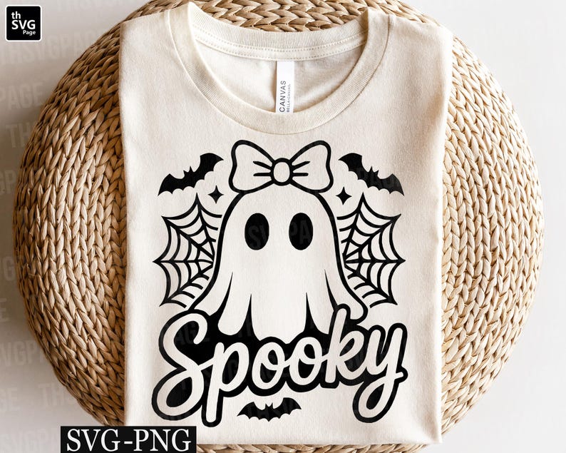 May include: Cream-colored t-shirt featuring a black graphic of a ghost with a bow, spiderwebs, and bats. The word "Spooky" is written in a script font below the ghost. The shirt is made of a soft material.