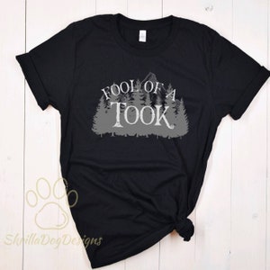 May include: Black t-shirt with a gray graphic print of a mountain range and trees with the text "Fool of a Took" in a stylized font.