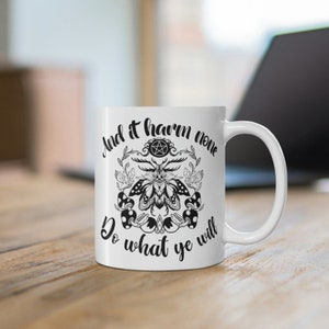 May include: White ceramic mug with a black and white graphic of a moth with a pentagram and the text "And it harm none Do what ye will".
