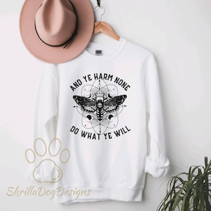 May include: White sweatshirt with a black and white graphic of a moth with a skull inside its wings. The graphic is surrounded by a circle with the text "And Ye Harm None Do What Ye Will".