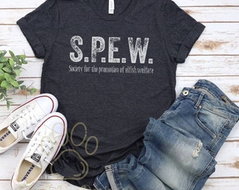 May include: A dark gray t-shirt with the text "S.P.E.W. Society for the promotion of elfish welfare" printed in white. The shirt is shown on a wooden surface with a pair of white sneakers and blue jeans.