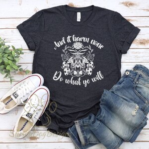 May include: A dark gray t-shirt with a white graphic design featuring a pentagram, a moth, and the text "And it harm none Do what ye will".