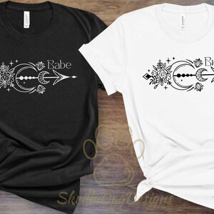May include: Two black and white t-shirts with a moon, arrow, and floral design. One shirt says "Babe" and the other says "Bride".