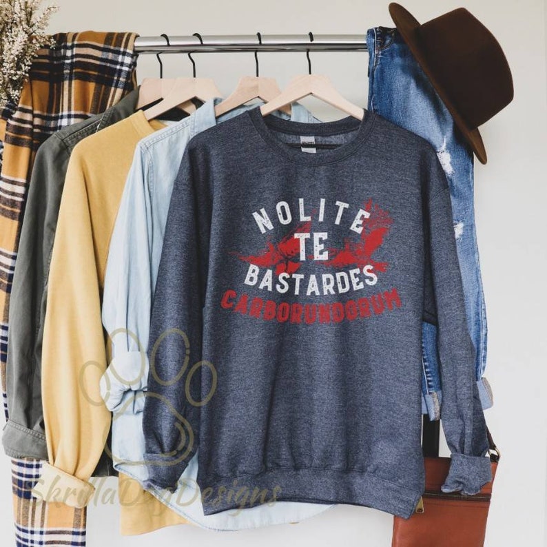 May include: A dark grey sweatshirt with a red graphic print that says "Nolite Te Bastardes Carborundum".