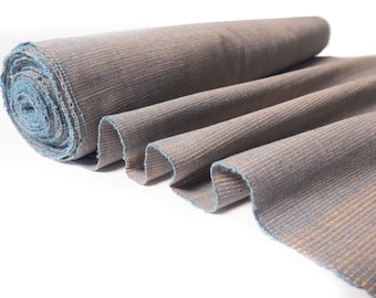 May include: A roll of brown and blue fabric with a textured weave. The fabric is folded and rolled up, showing the texture and color.