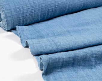 May include: A close-up of a light blue fabric with a textured surface. The fabric is folded in a few places, showing the texture and color.