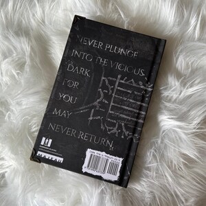 May include: Black hardcover book with the text "Never plunge into the vicious dark for you may never return." The book has a barcode and the word "Maleah" on the back cover.