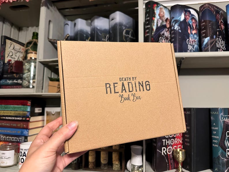 May include: A brown cardboard box with the text "DEATH BY READING Book Box" printed on the front.