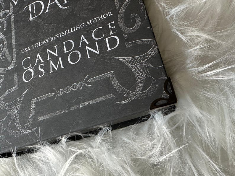 May include: Close-up of a black book with a silver embossed design and the text "USA TODAY BESTSELLING AUTHOR CANDACE OSMOND".